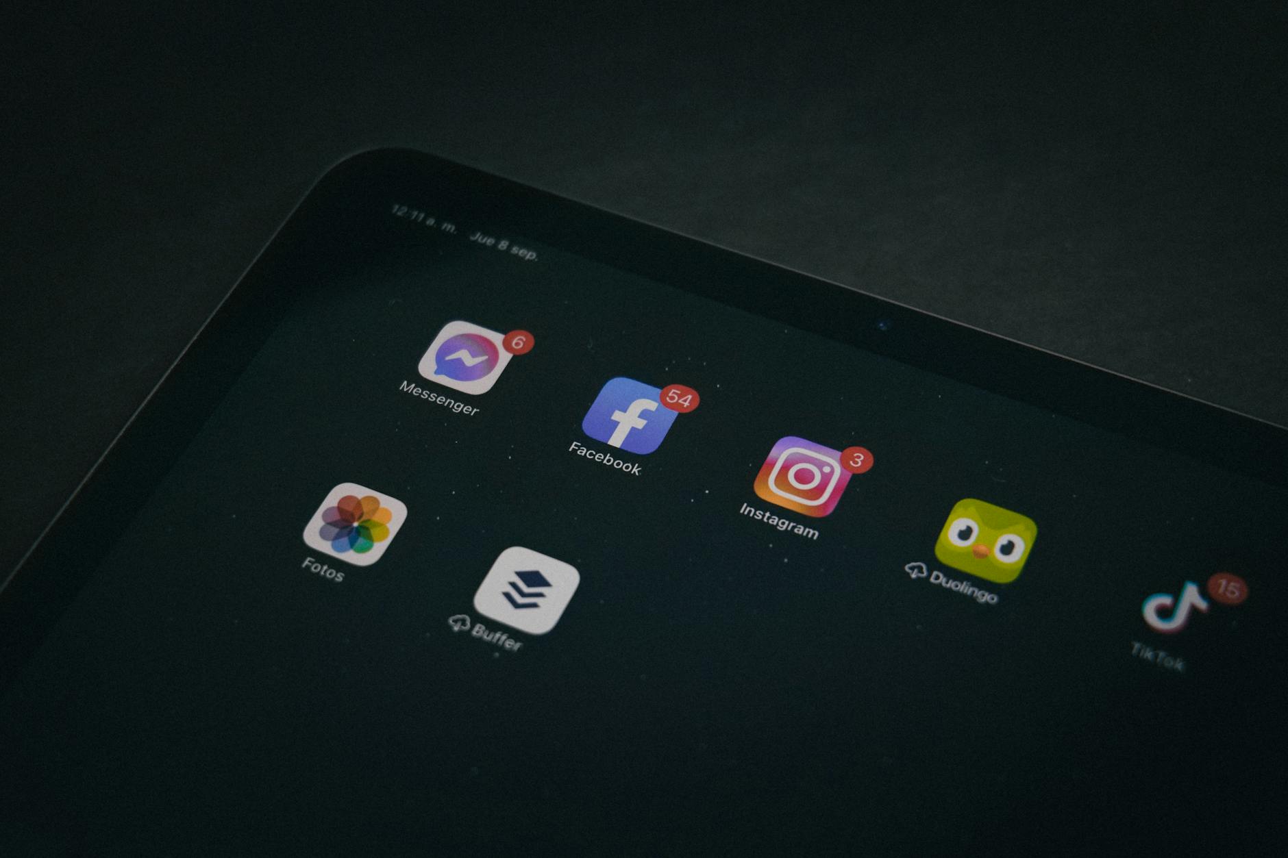 A tablet displaying popular apps like Facebook and Instagram in a dimly lit setting.